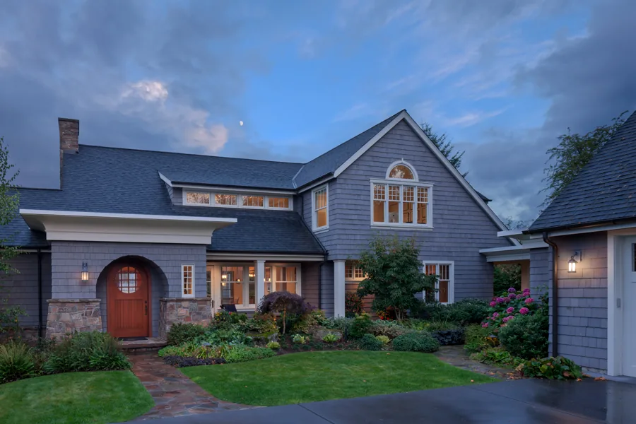 The Roanoke Residence features grey shingle siding, a gable roof, and a stone base with landscaped front yard.