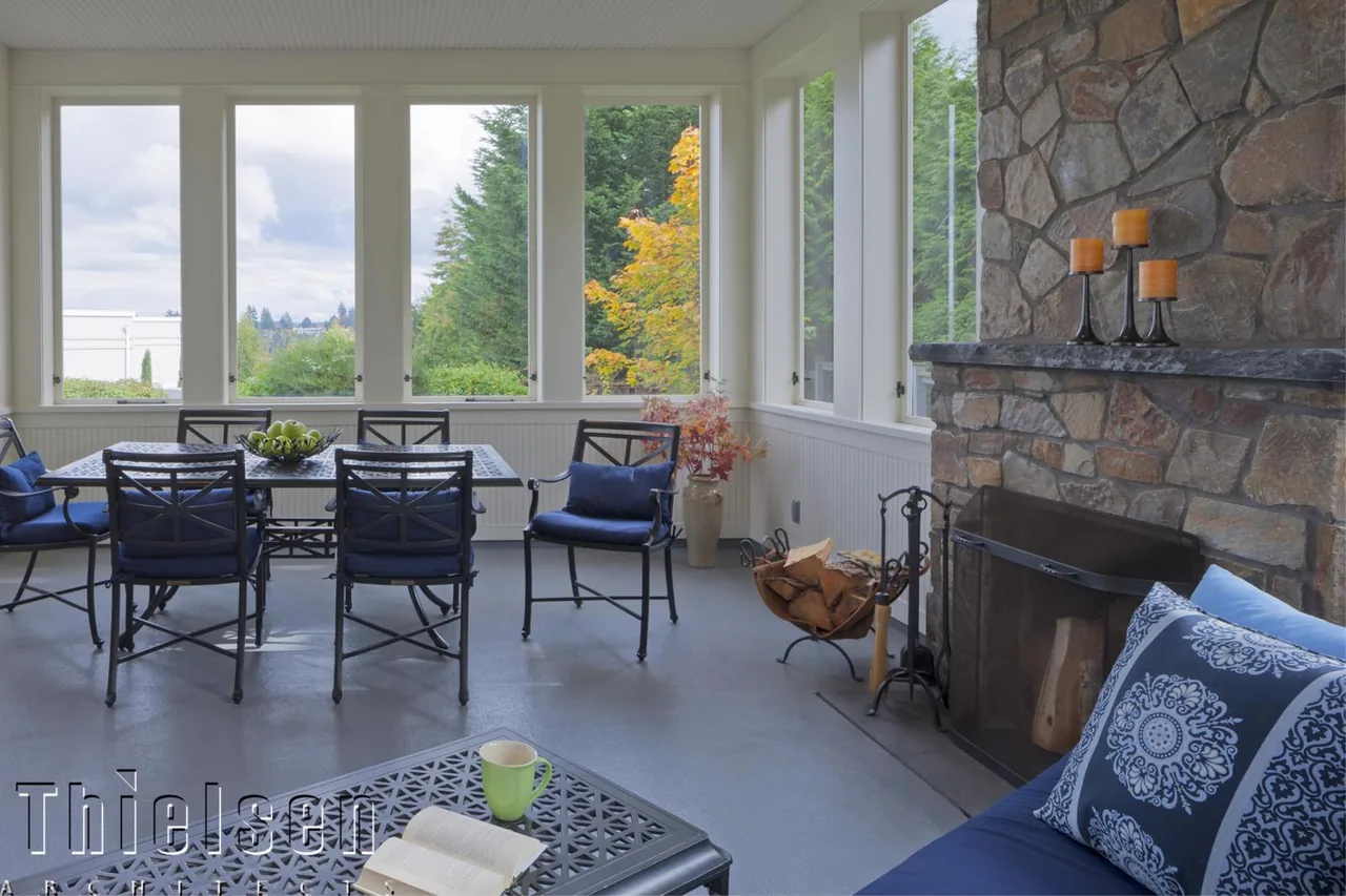The Roanoke Residence features a sunlit indoor dining area with floor-to-ceiling windows and a stone fireplace.