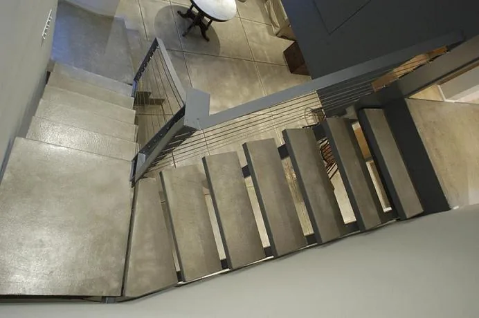 Modern concrete staircase with metal railing and cable detailing at Half-life House.