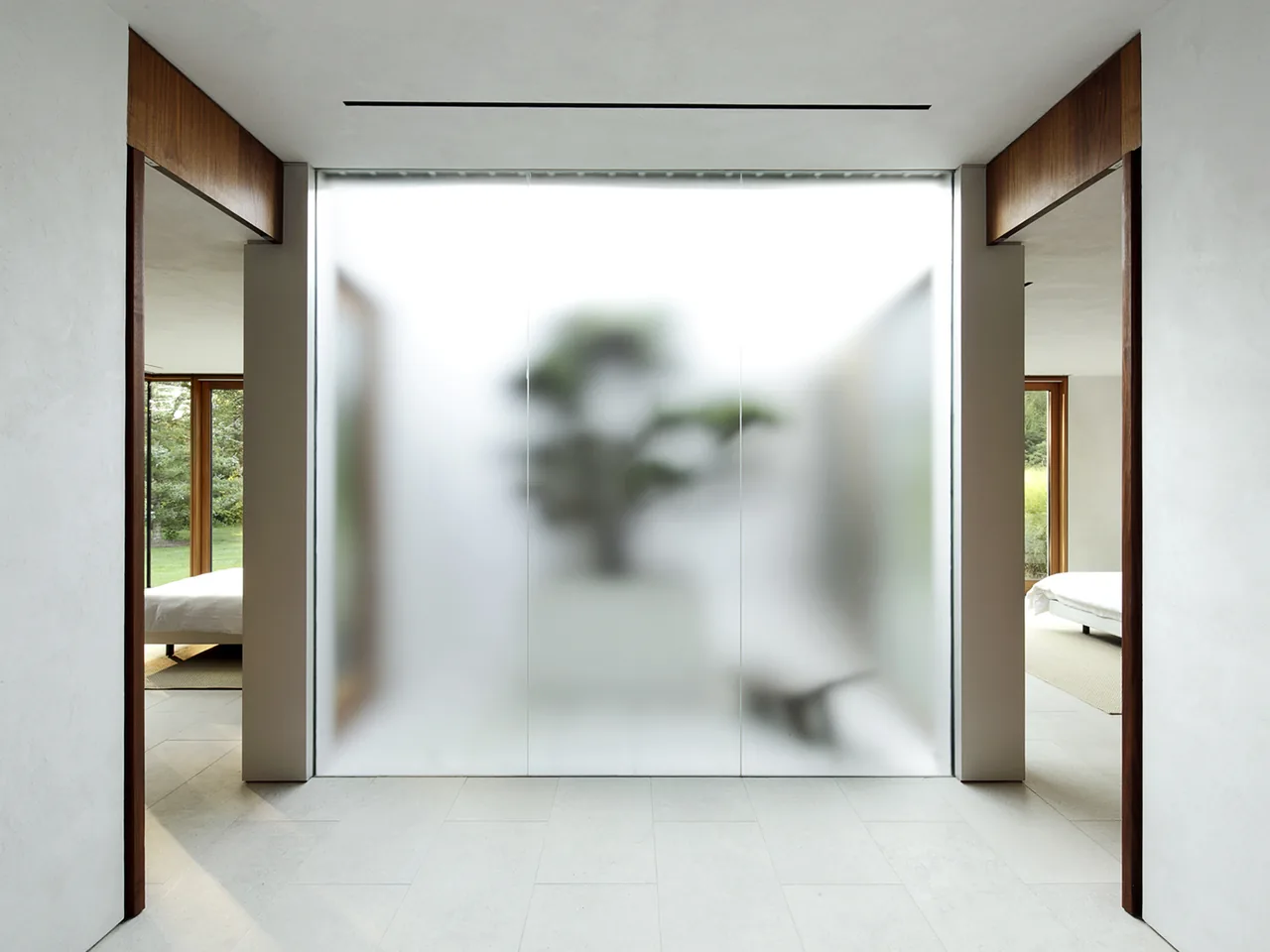 Hallway with a central frosted glass wall and views into bedrooms with large wood-framed windows.