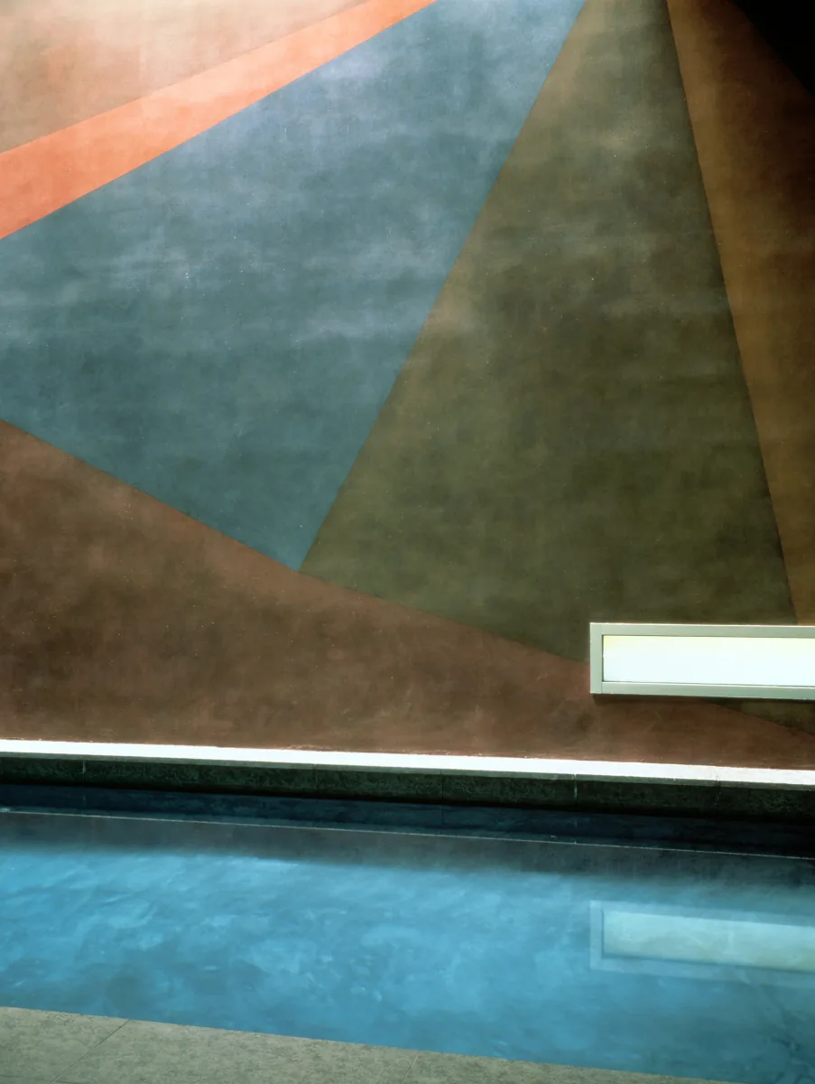 Pool adjacent to a wall with a geometric mural composed of large colored triangles.