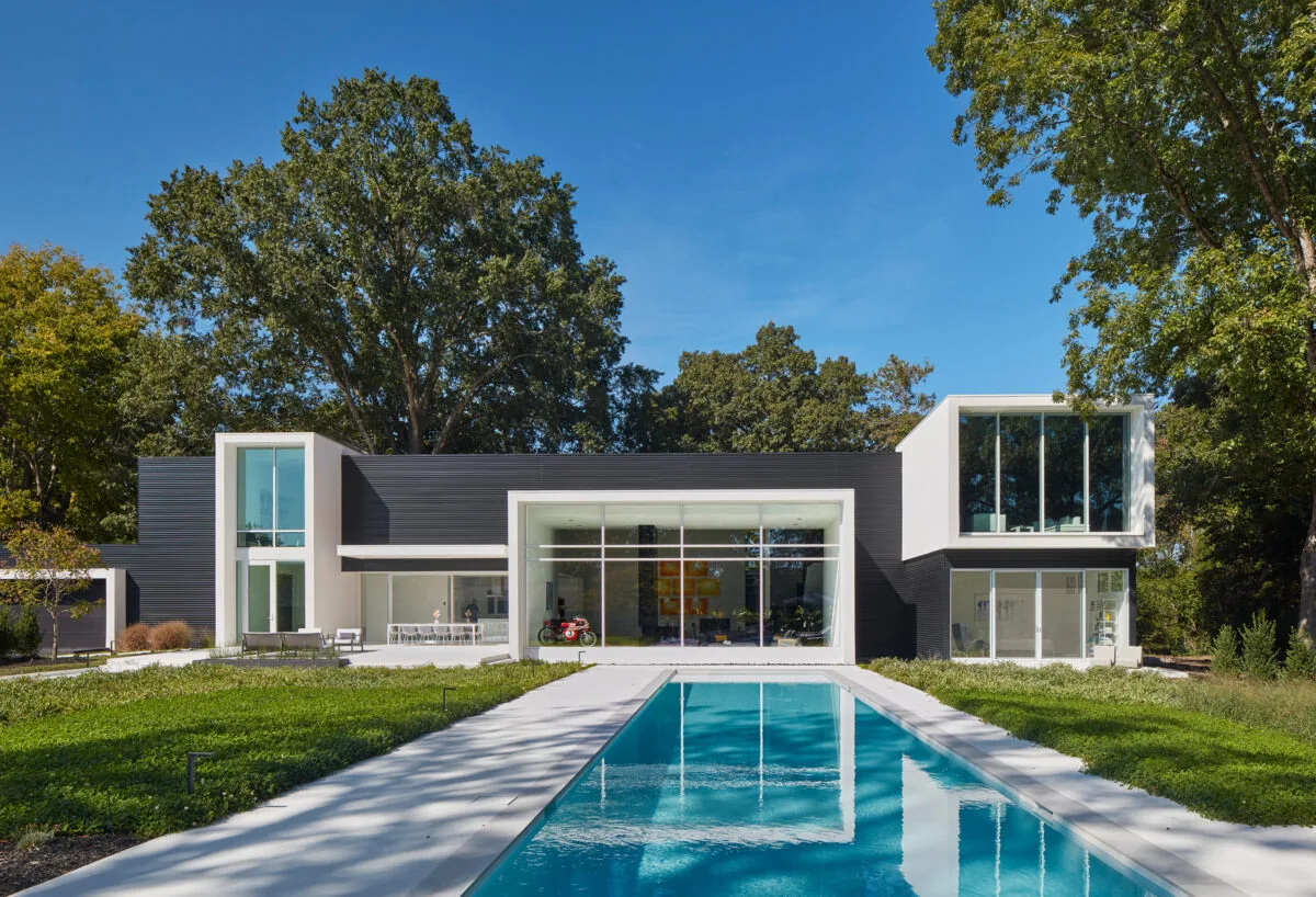 Frame House features a black and white contrasting facade with floor-to-ceiling glazing and a long outdoor pool.