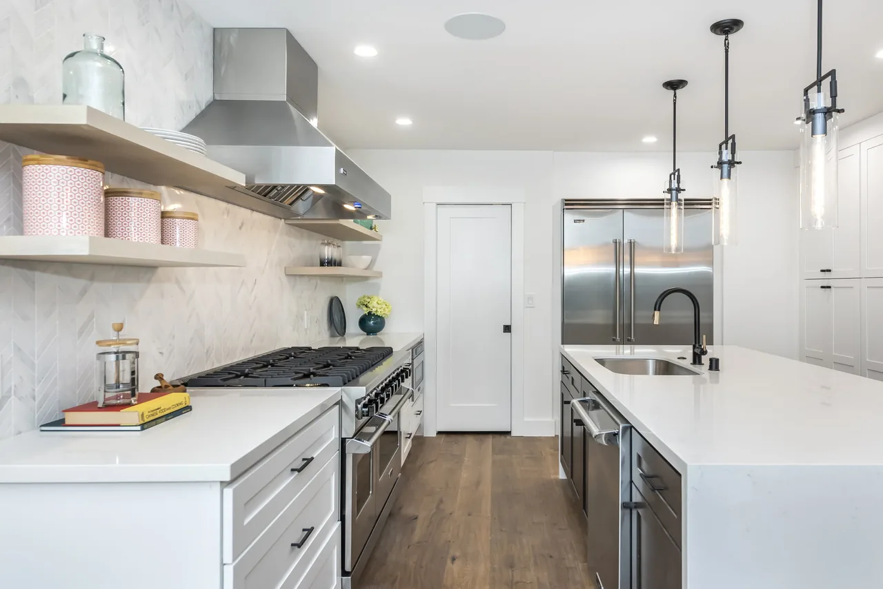 Forrest Edge kitchen features white cabinetry, stainless steel appliances, a large island, and modern pendant lighting.