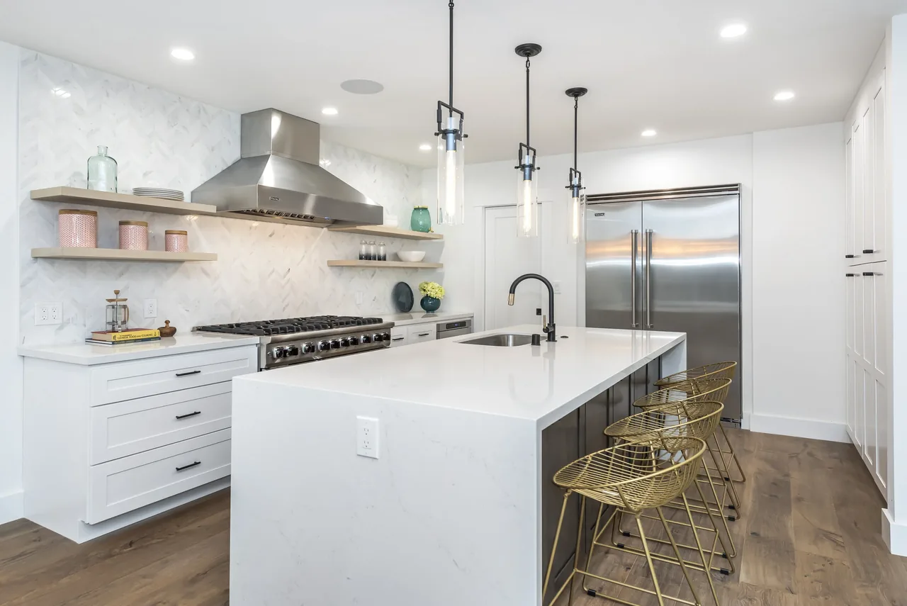 Kitchen in the Forrest Edge project by Topetcher Architecture features a large white island and stainless steel appliances.