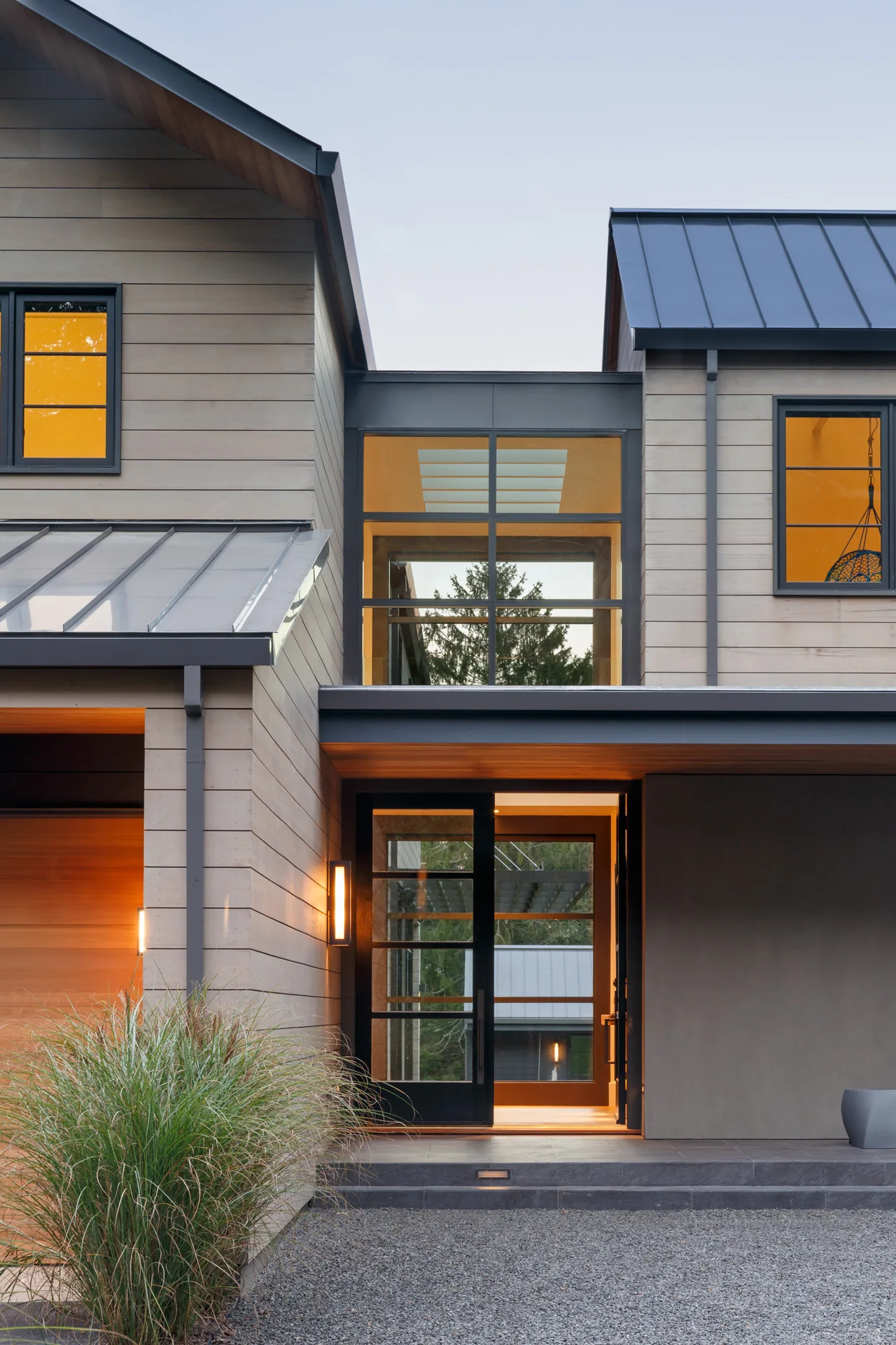 The WATERMILL RESIDENCE front exterior features metal roofs and large black-framed windows by CCS Architecture.