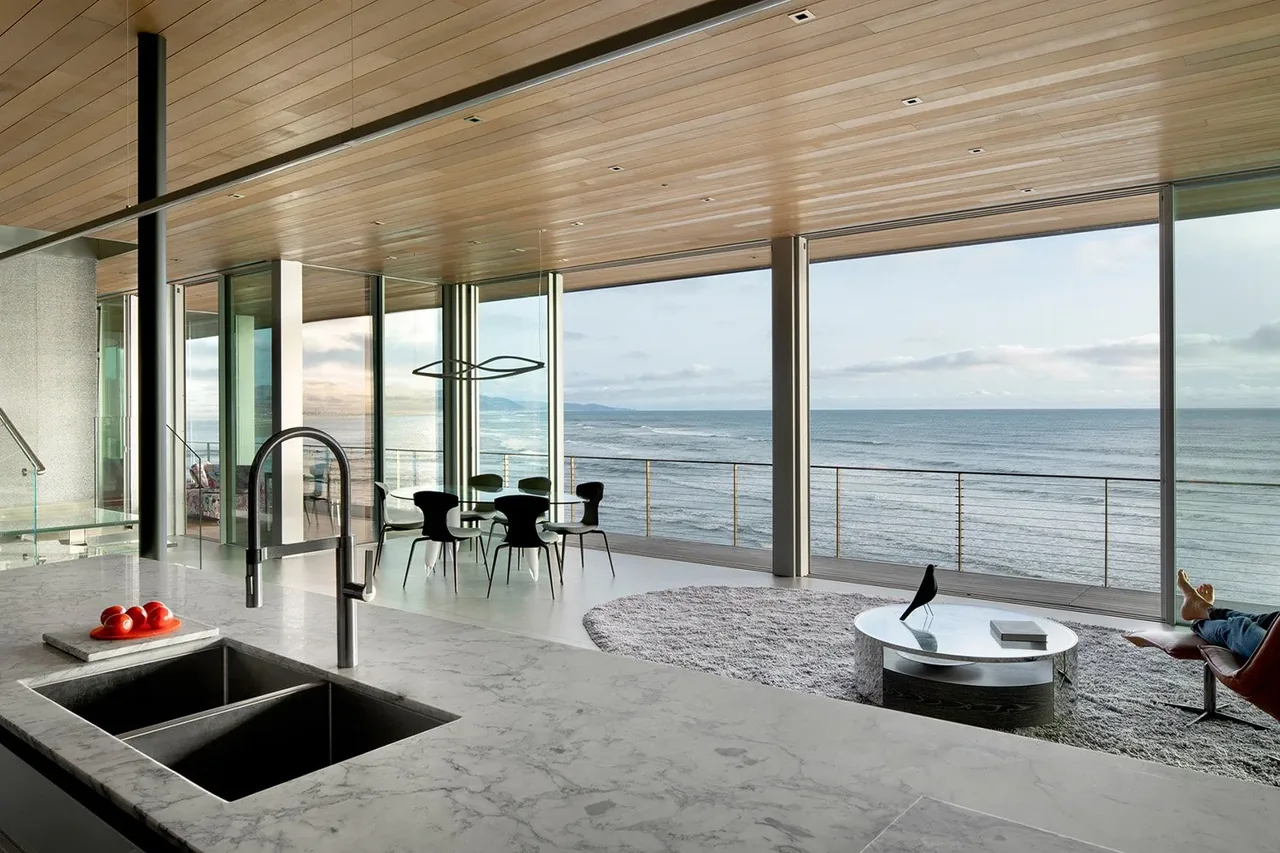 Open living and dining space with floor-to-ceiling glazing frames expansive ocean views in the Prow House by Chadbourne + Doss.