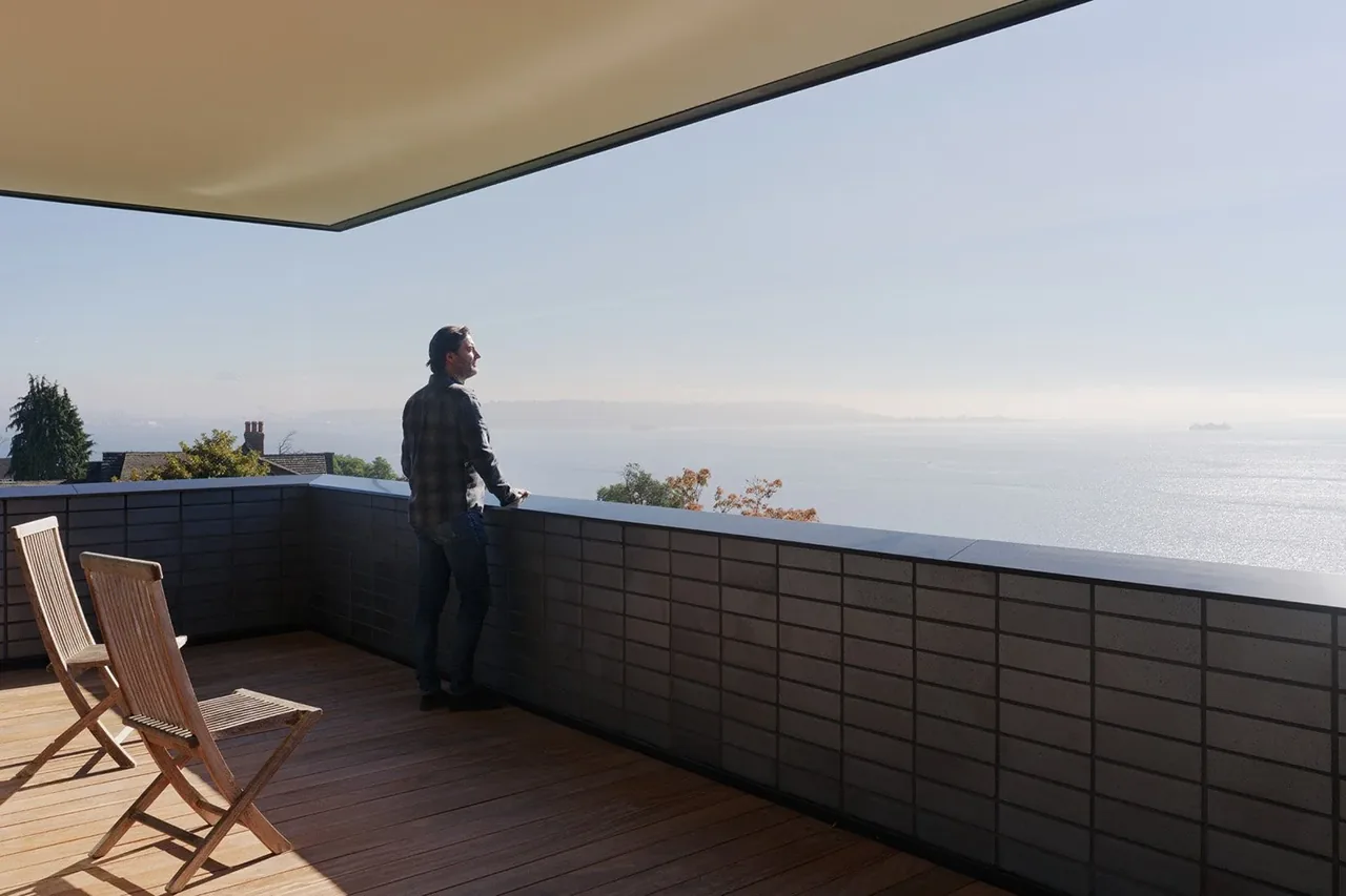 Covered outdoor deck with wooden flooring and a view of the water and distant land.