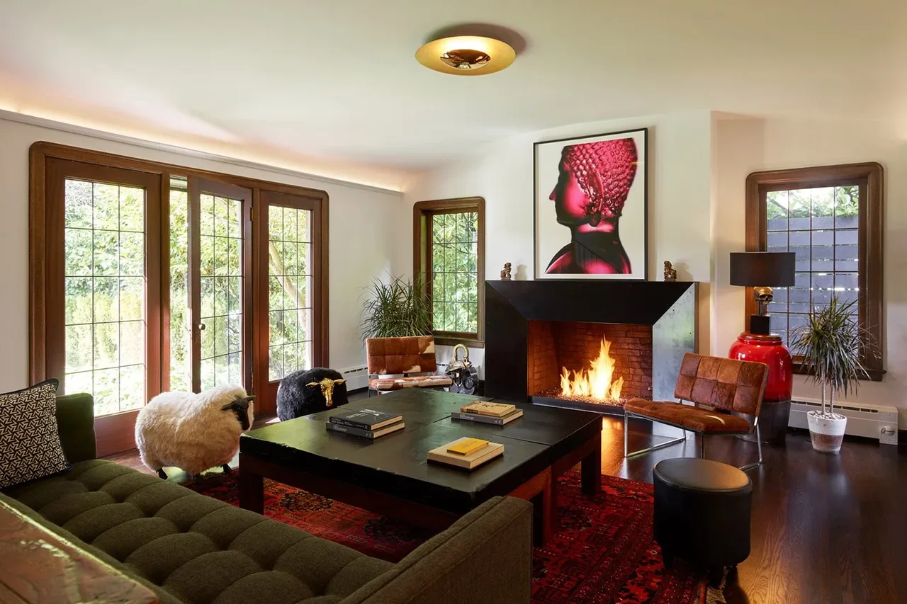 Living room with modern black fireplace, wood framed windows, and leather chairs in the Past Present House.