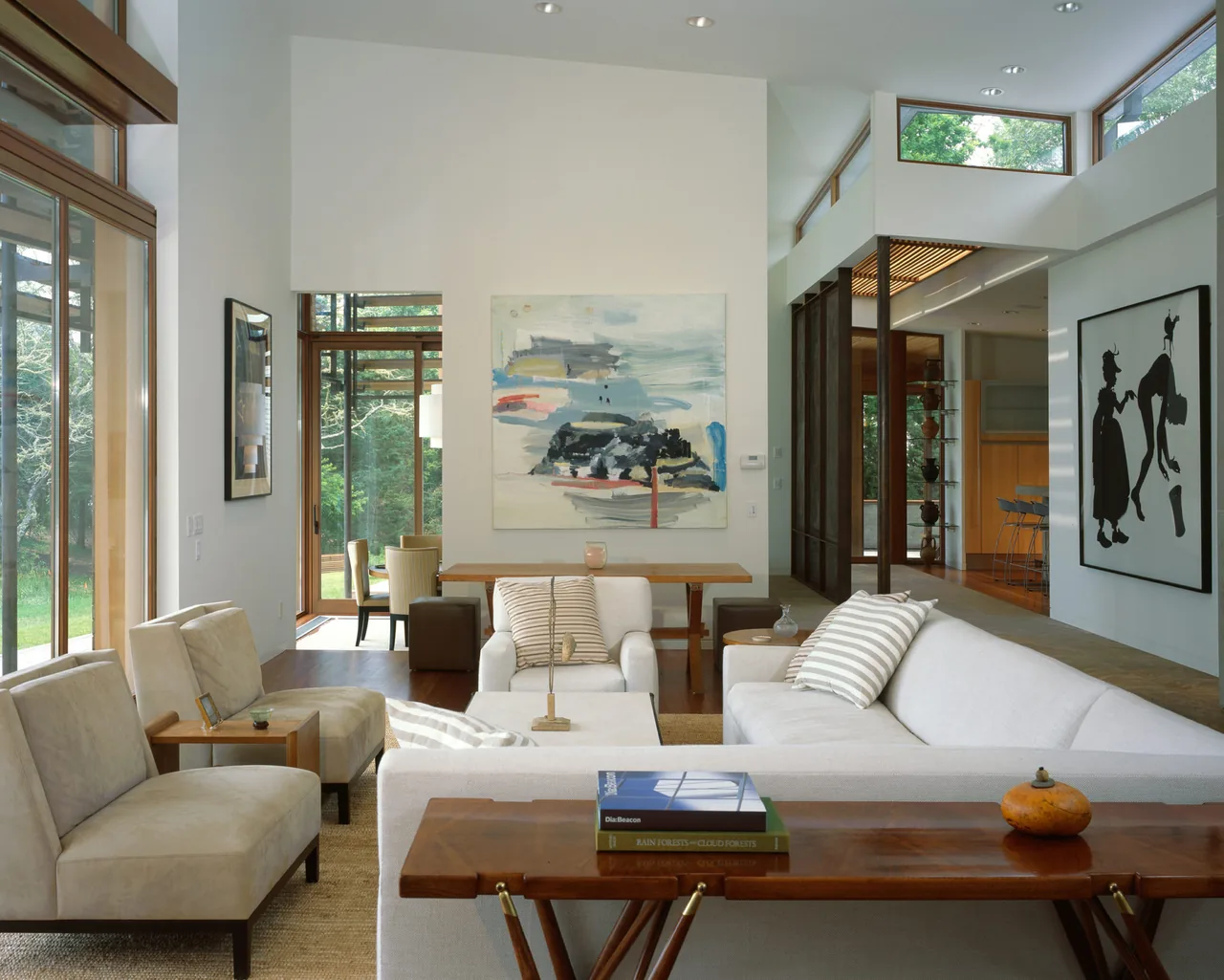 Living room of Orleans House features high ceilings, large windows, and contemporary furnishings with abstract and silhouette artwork.
