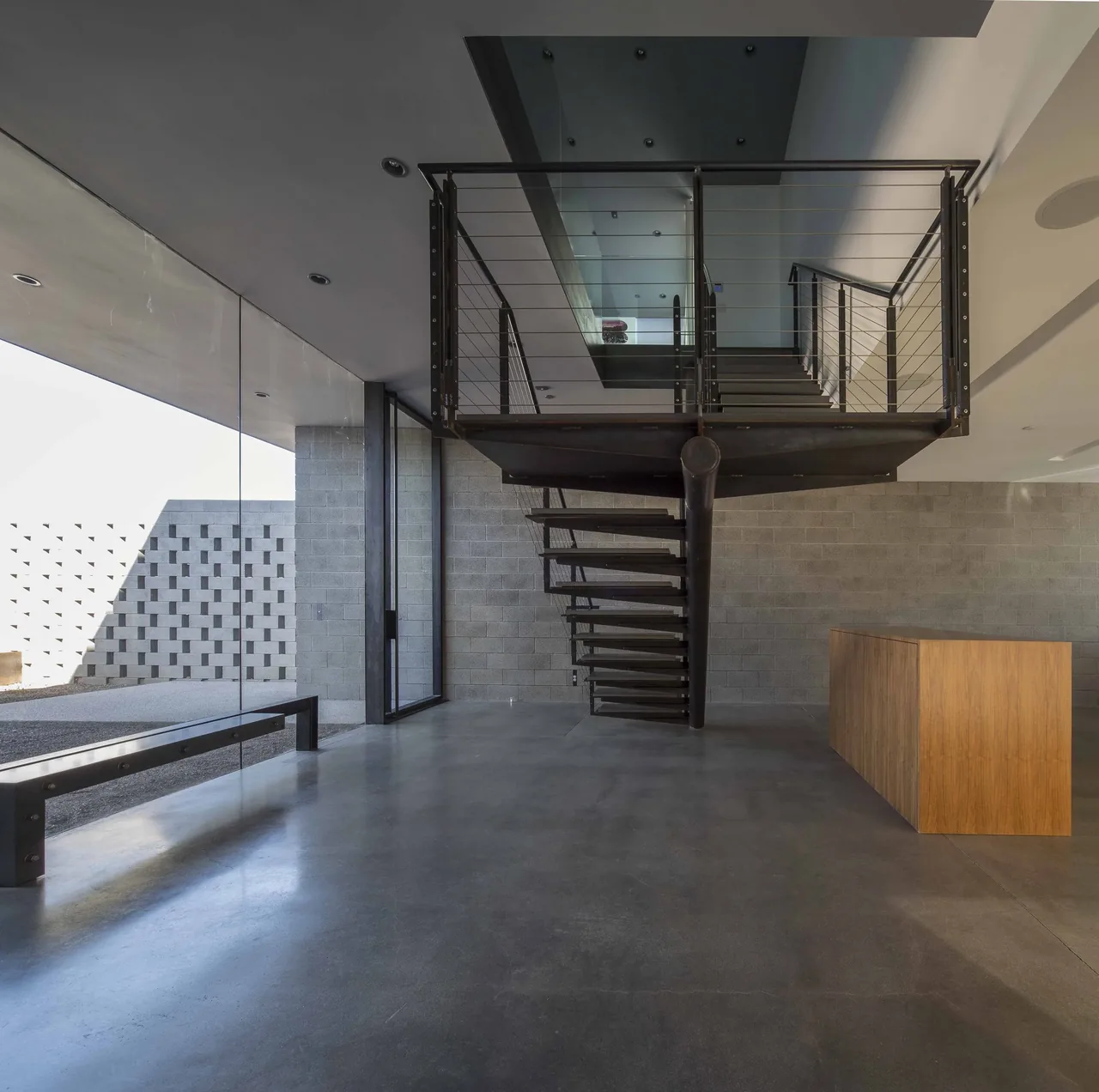 Modern floating metal staircase with cable railing in a concrete block walled interior of the Staab residence.