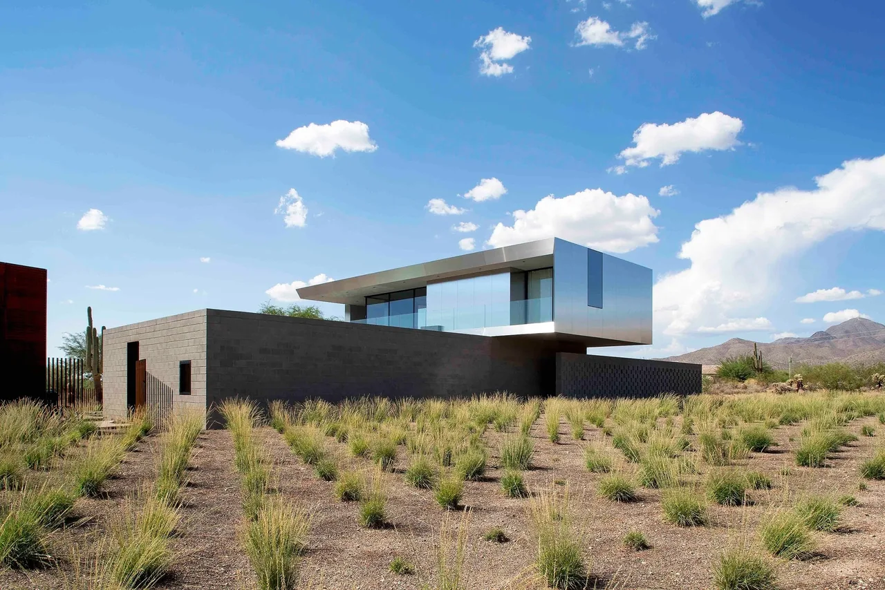 The Staab residence has a cantilevered metal and glass upper story above a concrete block base in a desert setting.