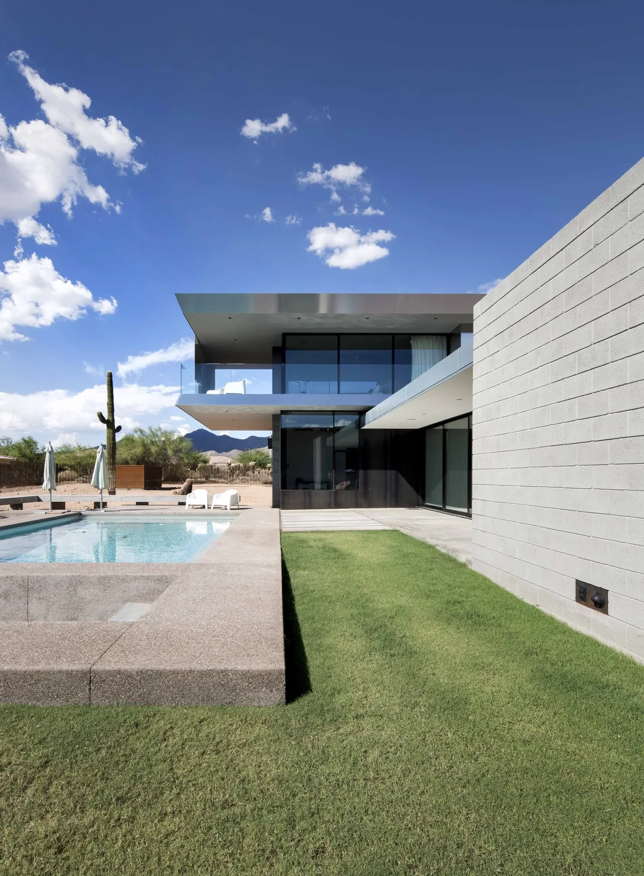 The Staab residence features a metal volume with block walls and a reflecting glass facade overlooking a pool and desert landscape.