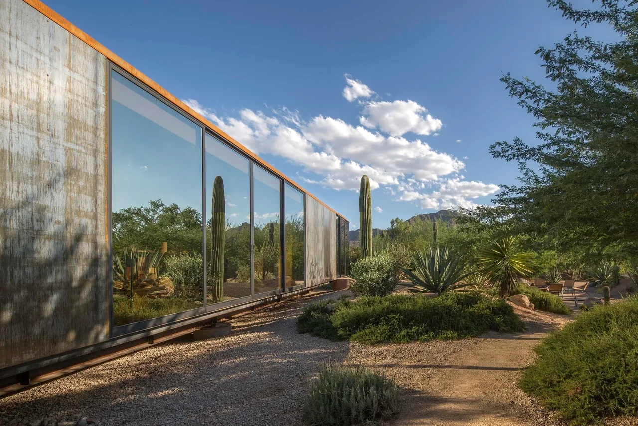 Project six features rusted metal siding and large floor-to-ceiling windows overlooking desert landscaping in Phoenix.