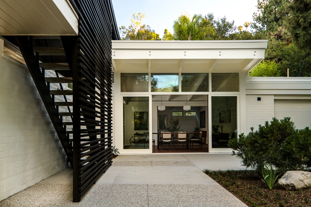 Veneklasen House exterior showing white beams and large sliding glass doors opening to dining area.