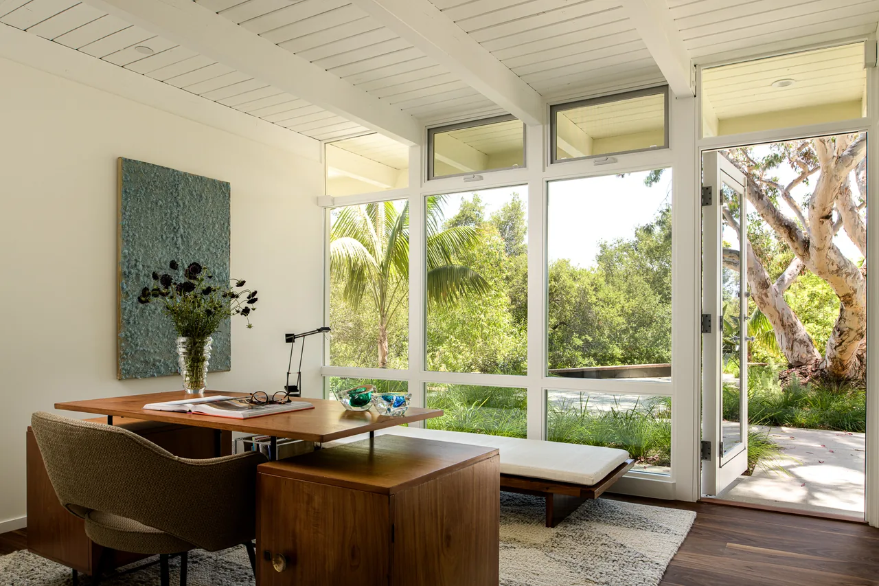 Office space in the Veneklasen House featuring expansive white window frames and dark wood furniture.