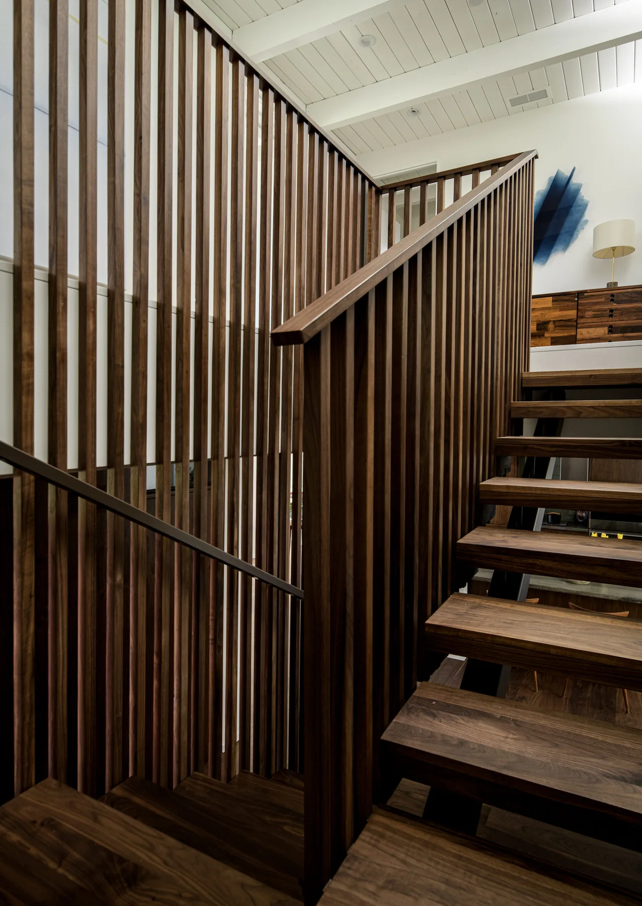 The Veneklasen House staircase features walnut wood open risers and a vertical slatted wooden screen railing.