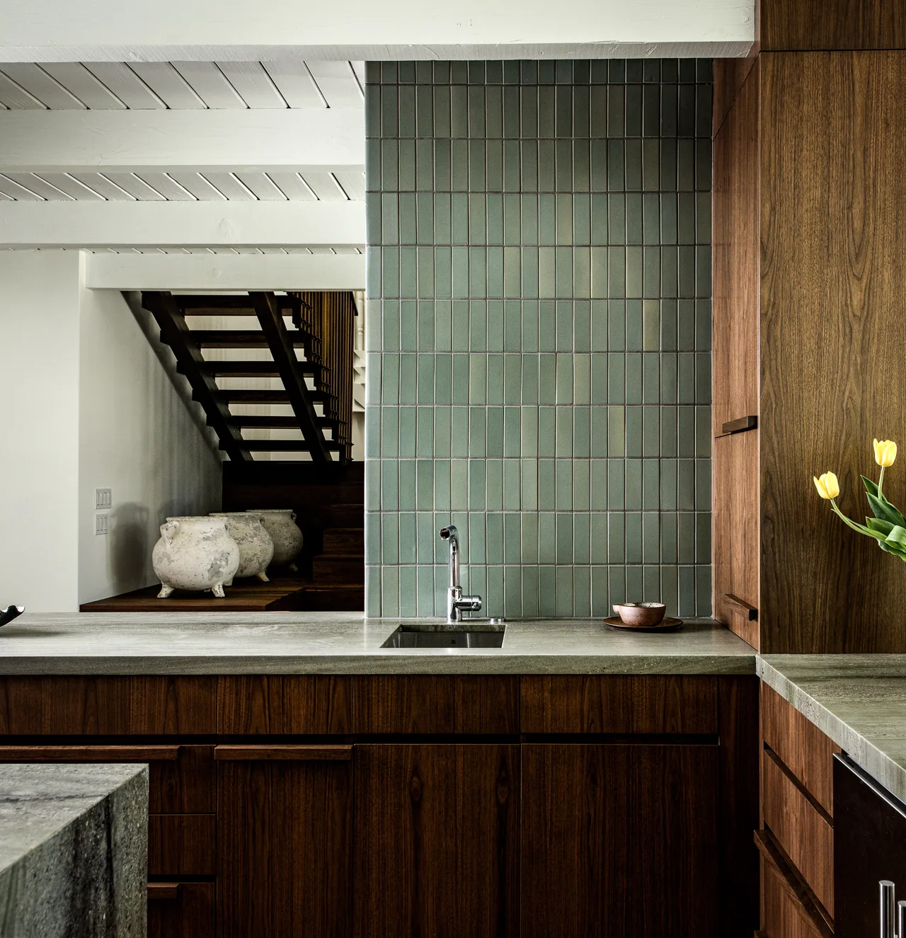Kitchen featuring dark wood cabinets, green tile backsplash, and concrete countertops at the Veneklasen House.