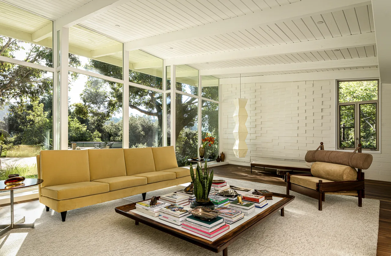 Veneklasen House living room by CHU+GOODING Architects features textured brick walls and two-story glazing with a yellow sofa.