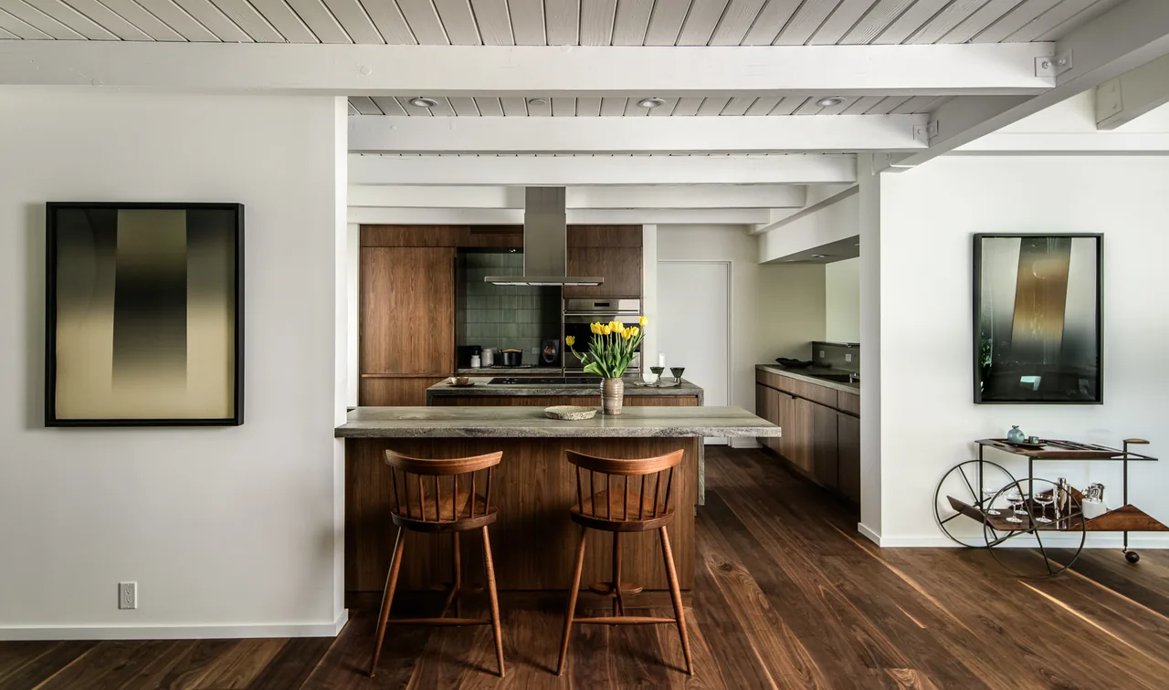 Modern kitchen with walnut cabinetry and island in Veneklasen House by CHU+GOODING Architects in Los Angeles.