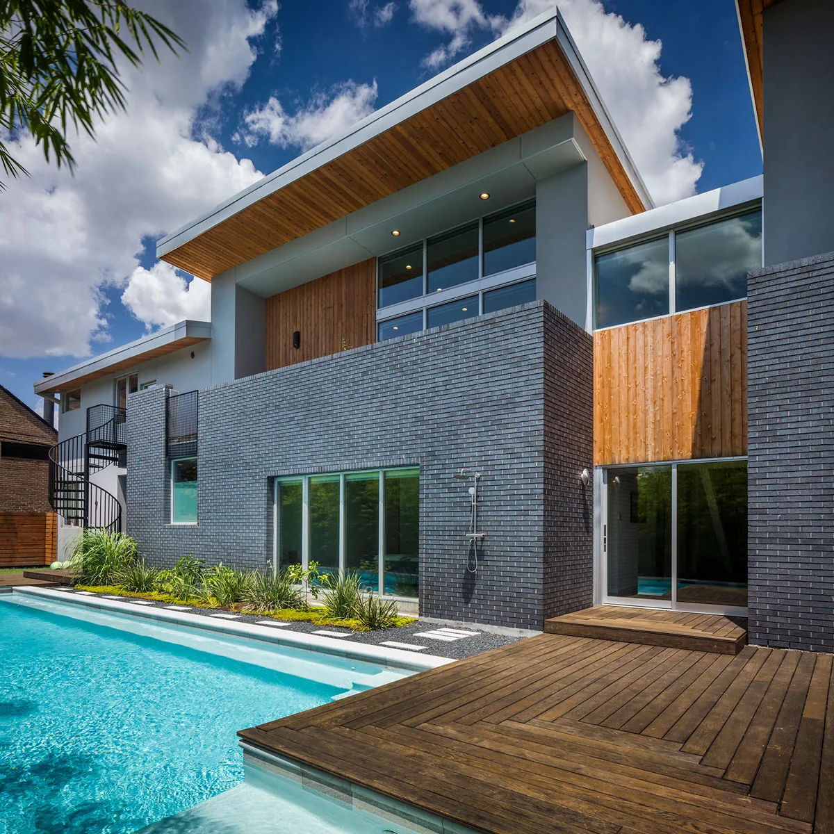 HOUSE 2344 features gray brick and wood paneling with a pool and wood deck in Houston.