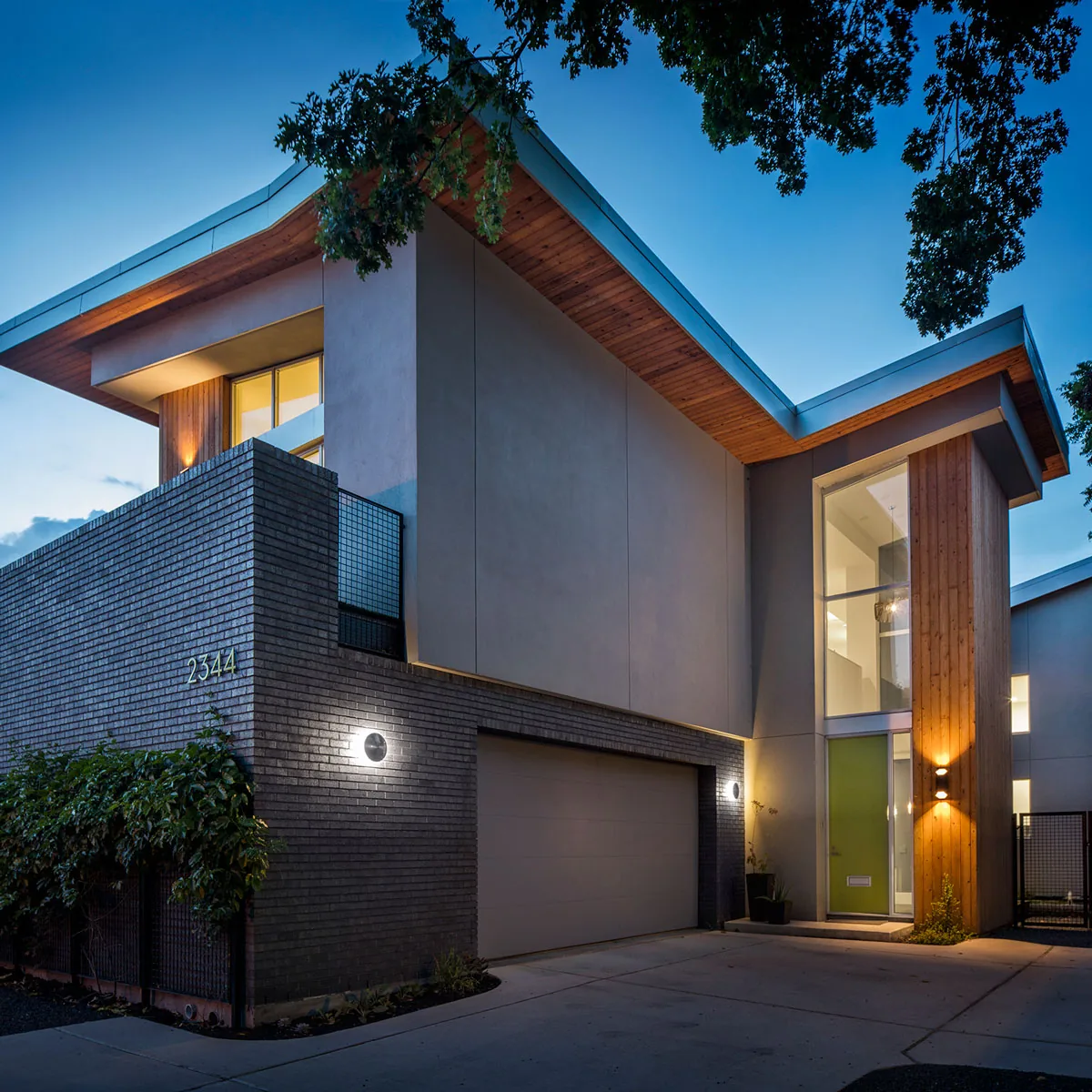 HOUSE 2344 by Collaborative Design Works features a modern facade with stucco, wood siding, and black brick accents in Houston.