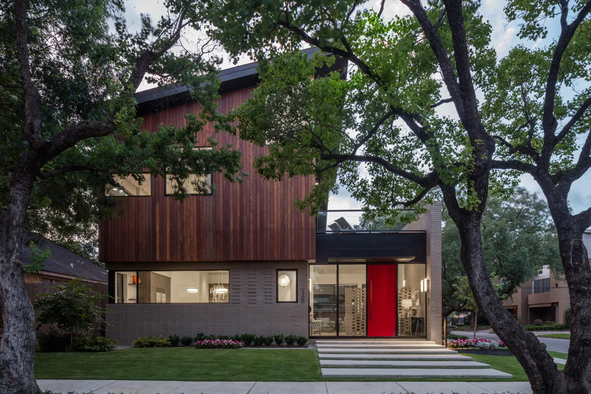 HOUSE 1700 is a modern two-story home with wood siding and brick exterior, showcasing a large red front door and ample glazing.