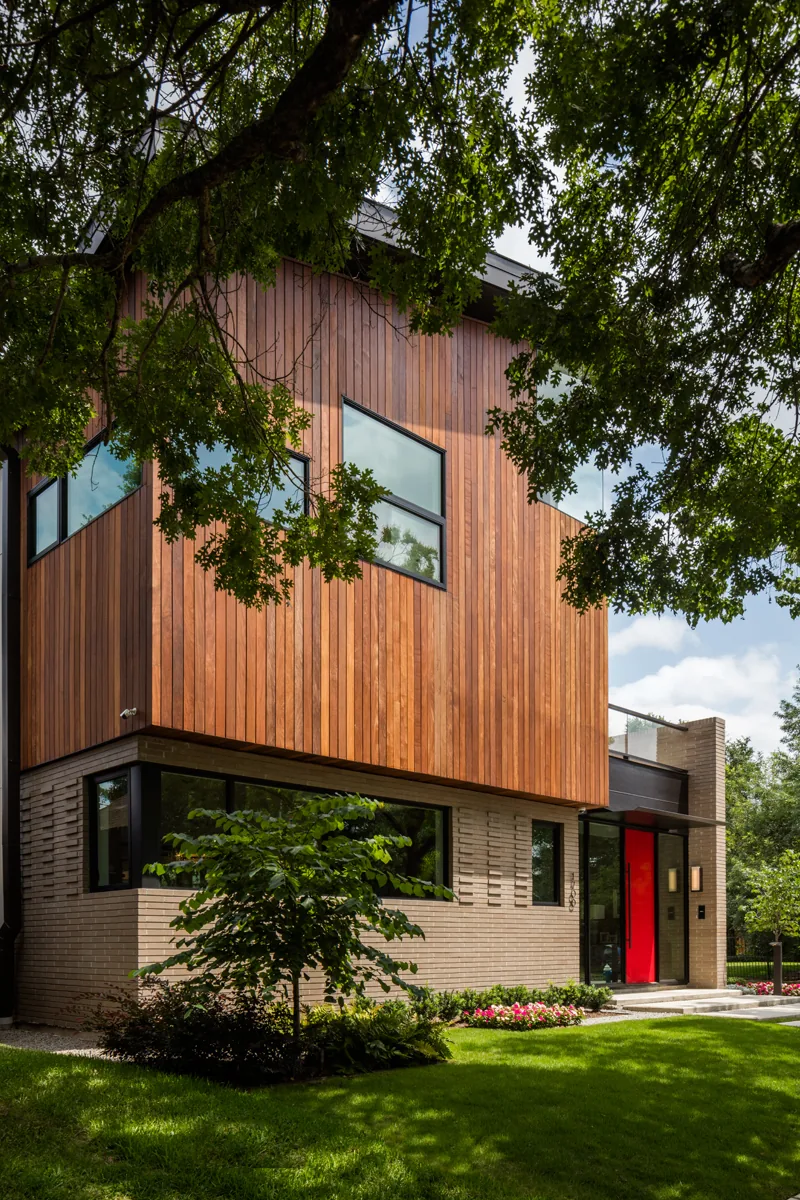 HOUSE 1700 by Collaborative Design Works is a modern home with wood and brick exterior and large black-framed windows.