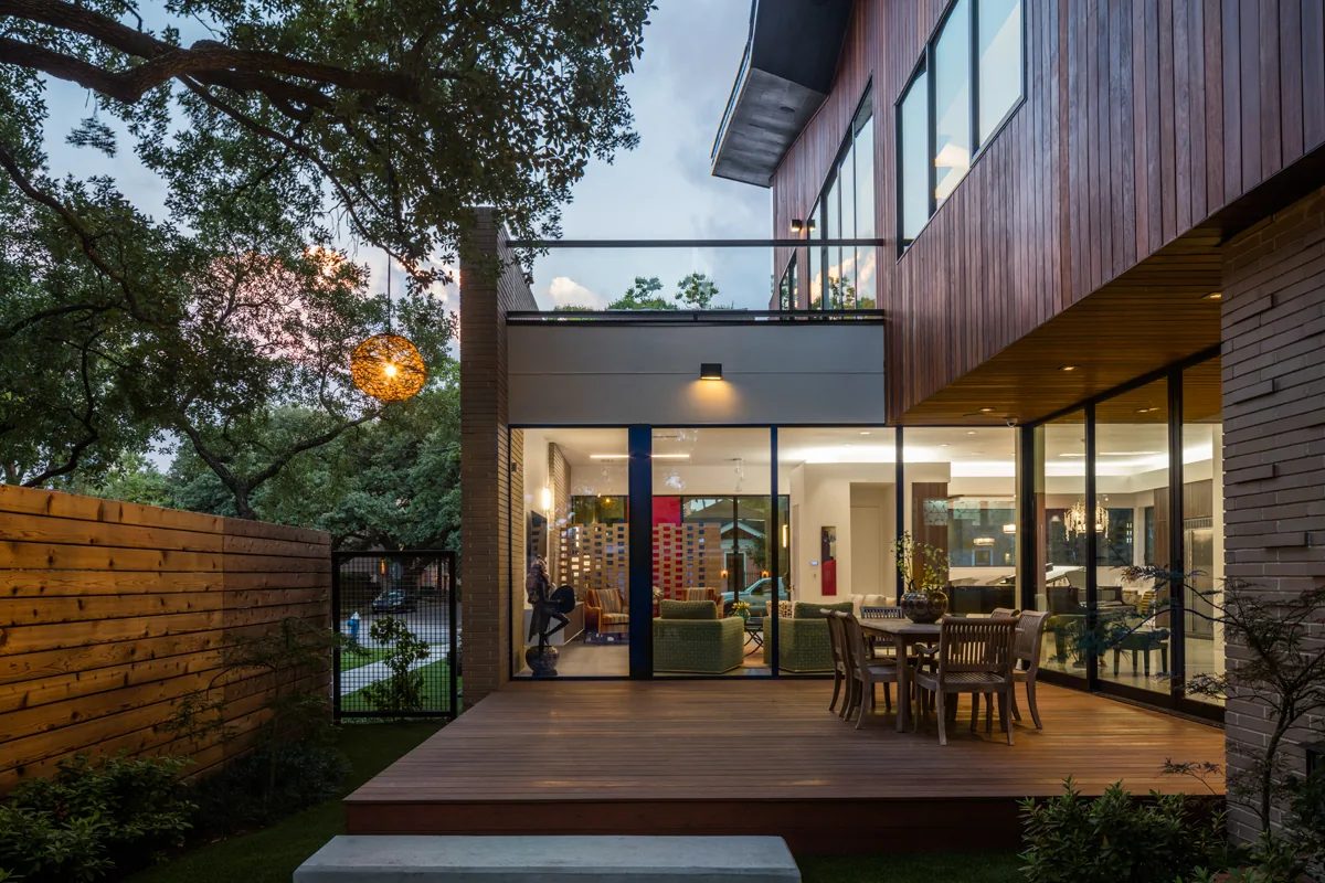 HOUSE 1700 features a wood deck patio with outdoor dining area and extensive floor-to-ceiling glass walls connecting indoor and outdoor spaces.