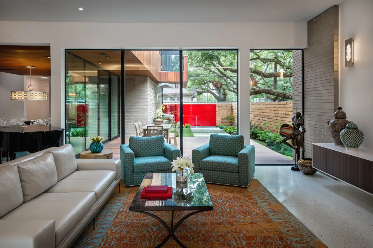 Living room features floor-to-ceiling windows with views of the backyard garden and red gate beyond glass sliding doors.