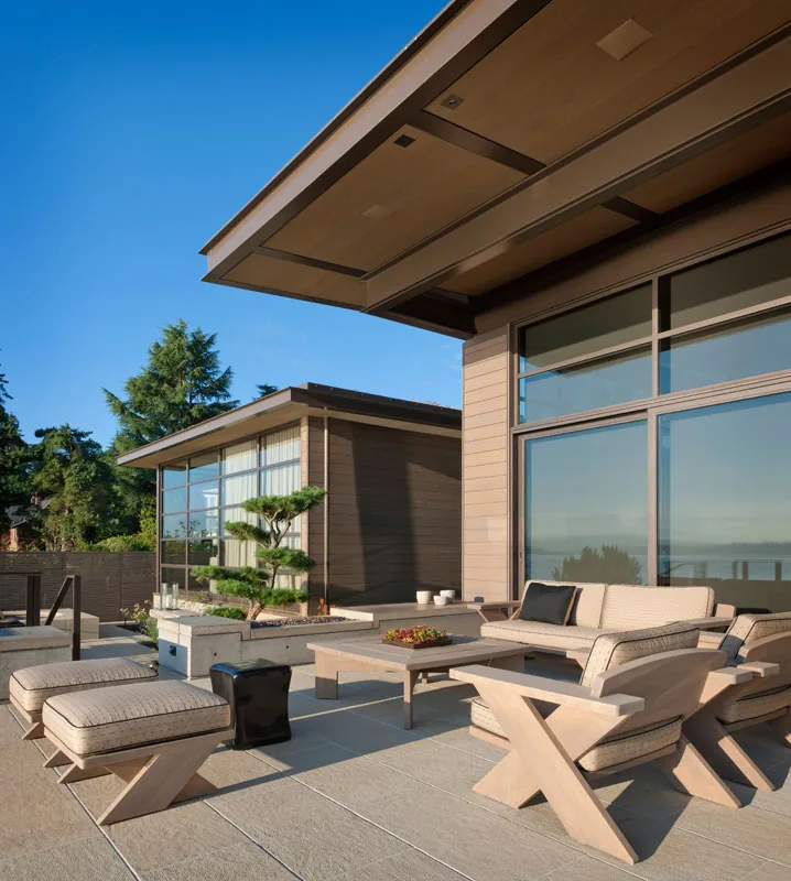 Washington Park Residence features a modern patio with wooden seating and large windows overlooking natural scenery.
