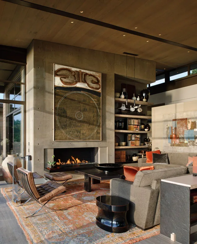 Living room with board-formed concrete fireplace, built-in shelving, and contemporary furniture at Washington Park Residence.