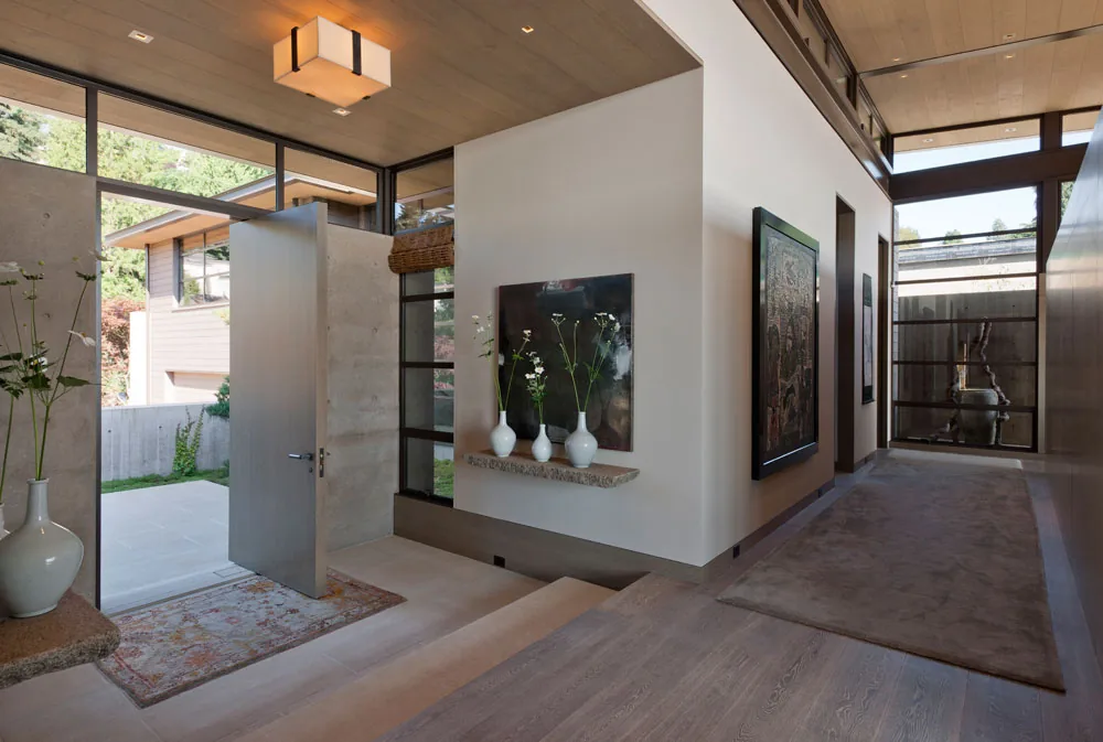 The Washington Park Residence entry showcases floor-to-ceiling glazing and a wood-paneled ceiling.