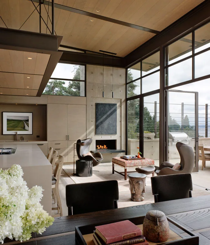 The Washington Park Residence features floor-to-ceiling glazing, a linear fireplace, and exposed wood ceiling beams in the living area.