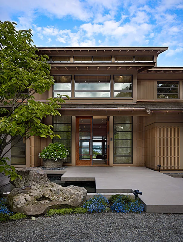 Exterior front view of Engawa House with concrete pathway, wooden siding, and landscaped garden elements.
