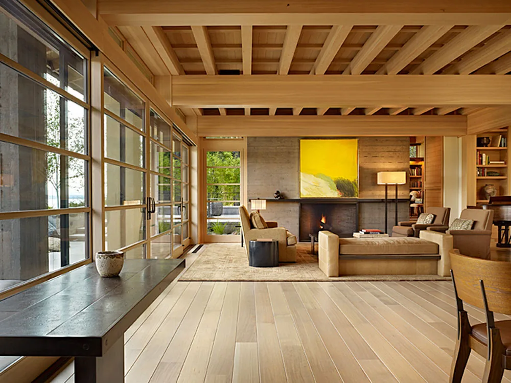 Living room featuring wood grid windows, a concrete fireplace, and exposed wooden ceiling beams in Engawa House.
