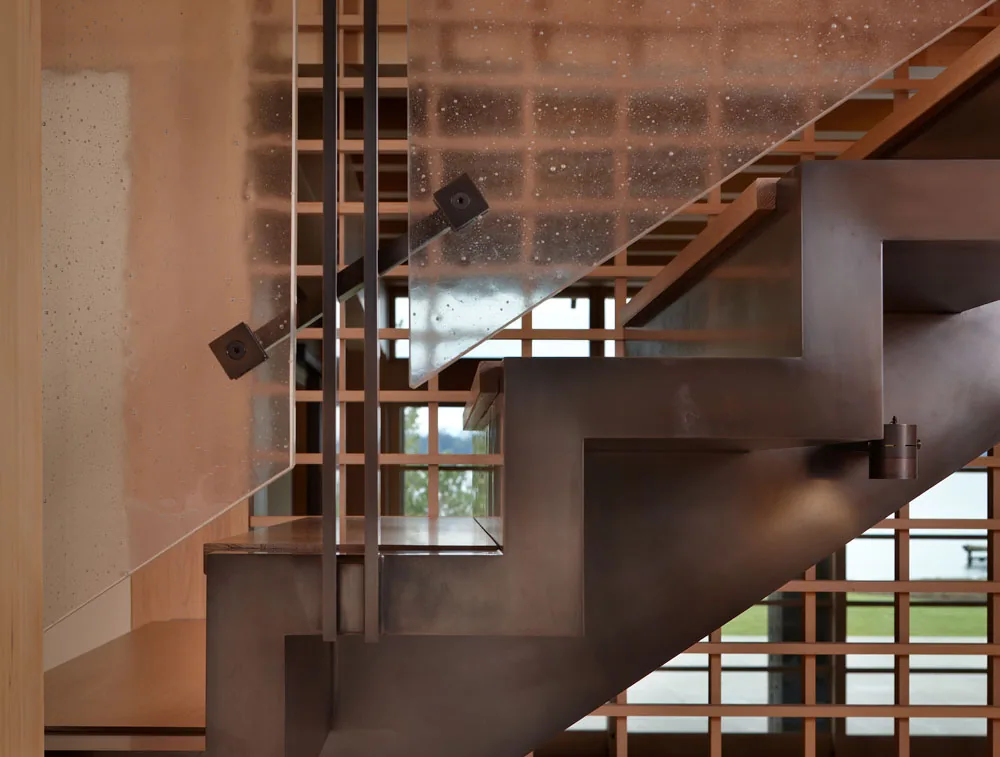Steel modern staircase with textured glass railing and wood grid window wall in Engawa House, Seattle.
