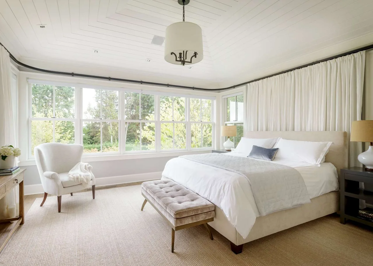 Modern farmhouse bedroom featuring large multi-pane windows with white trim and neutral-toned furniture.