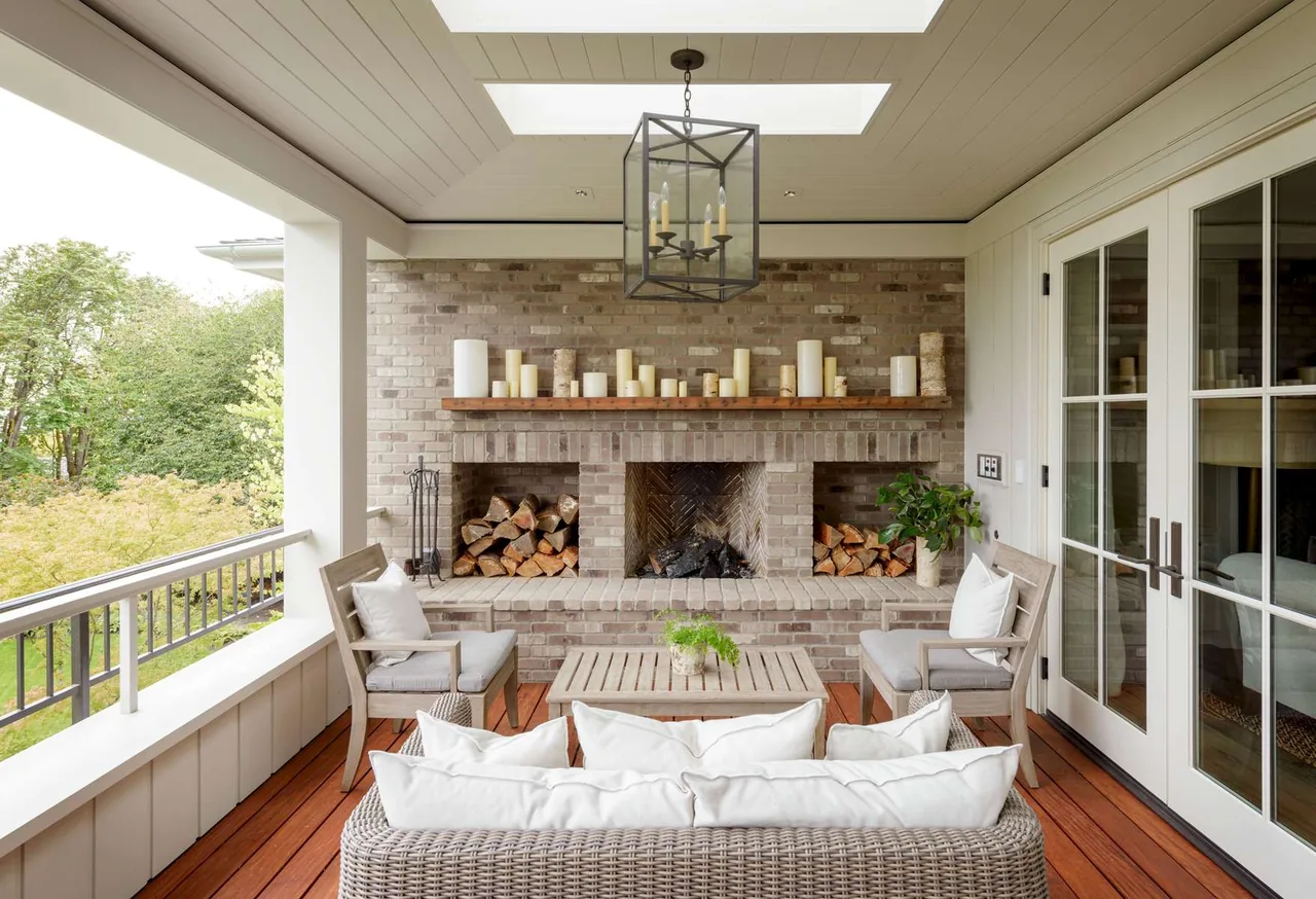 Outdoor living space features a brick fireplace with wood storage, cozy seating, and a hanging lantern light fixture under a skylight.
