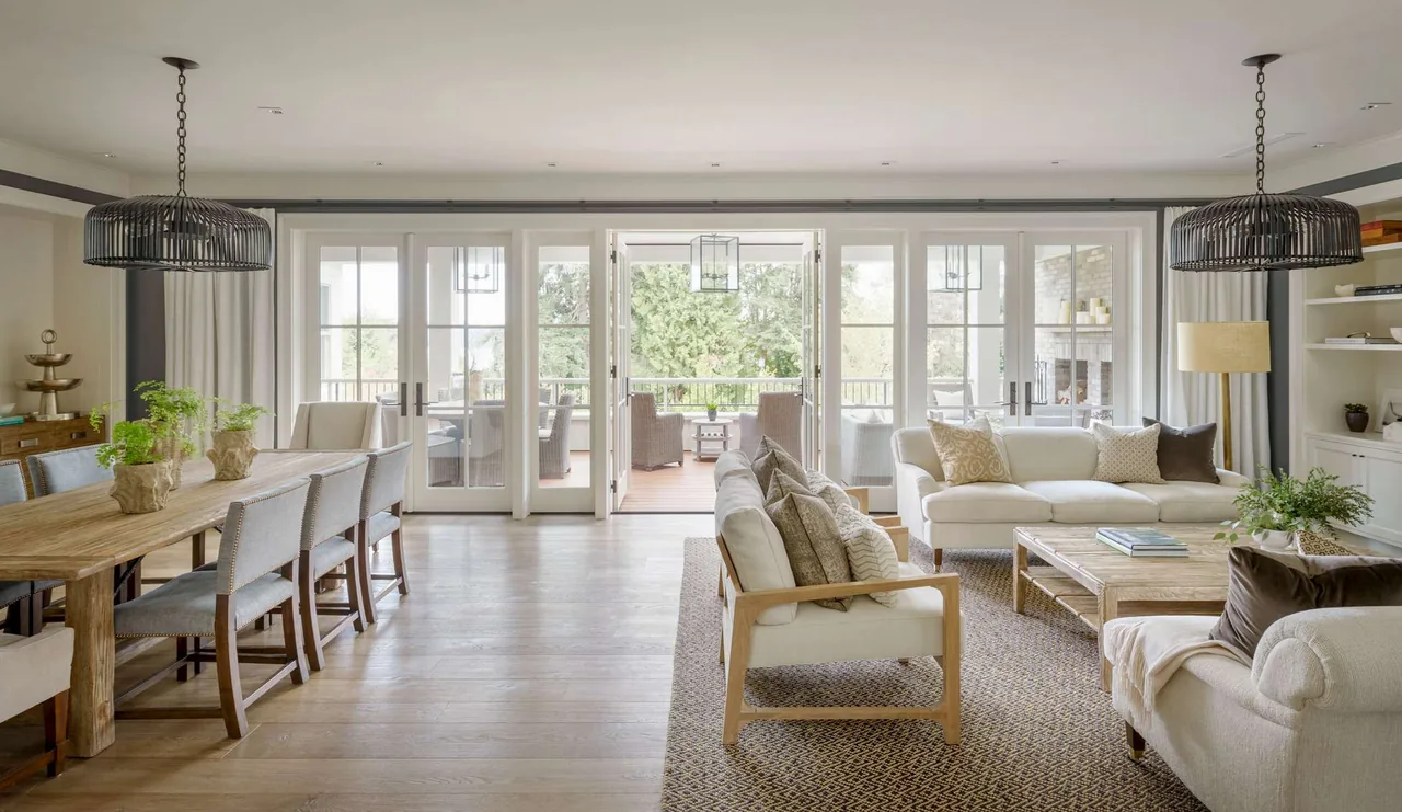 Open living and dining rooms open through French doors to an outdoor covered patio with seating and fireplace.
