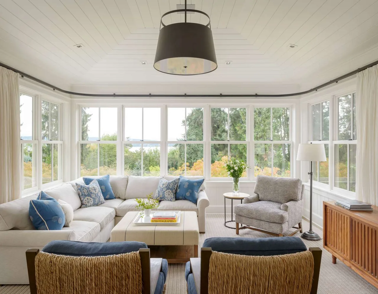Living room in a modern farmhouse with multi-pane windows, neutral tones, and blue pillows.