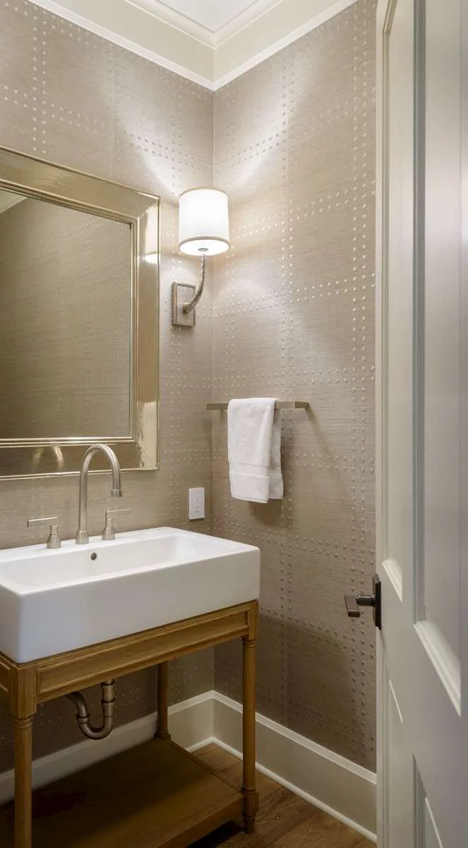 Small bathroom interior with a rectangular white sink on a wooden stand and beige textured wallpaper.