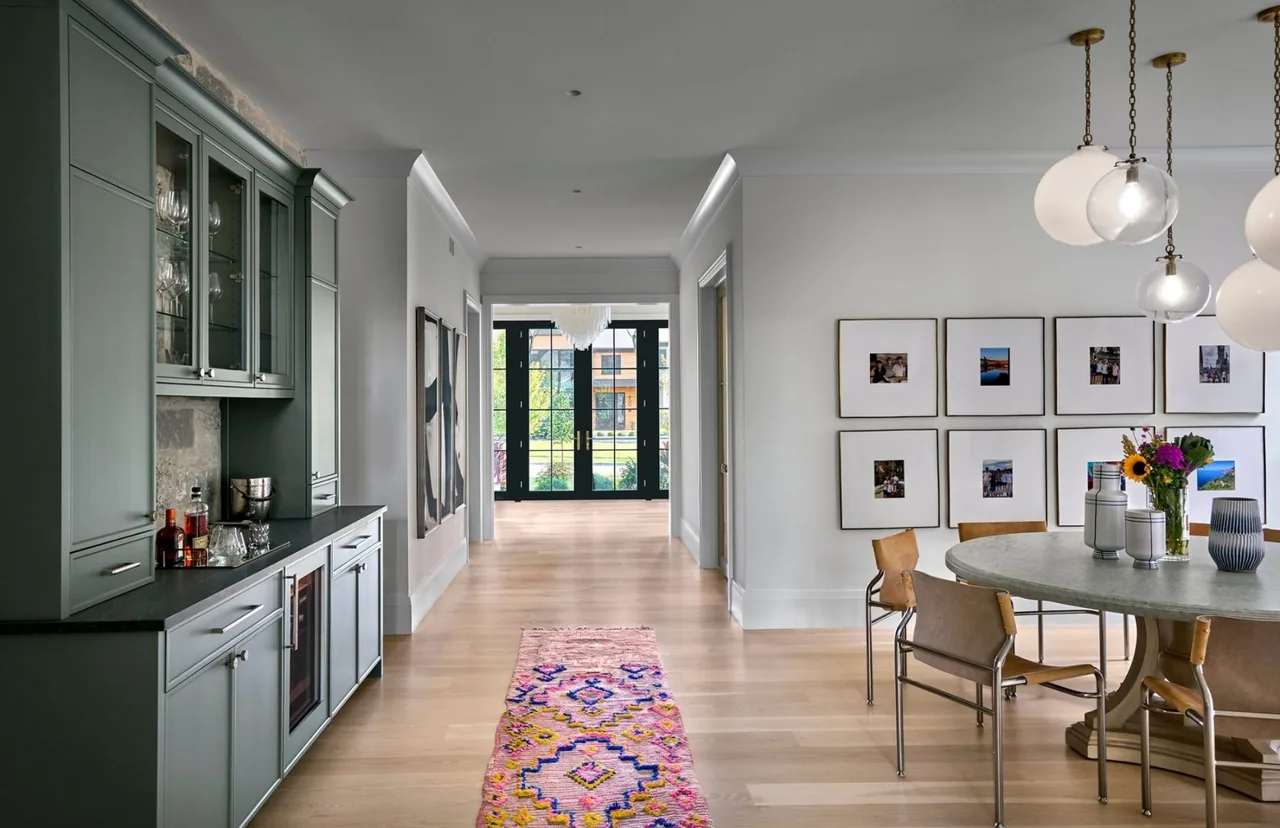 The transitional residence features black-framed glass doors open to the exterior and a dining area with pendant lighting.