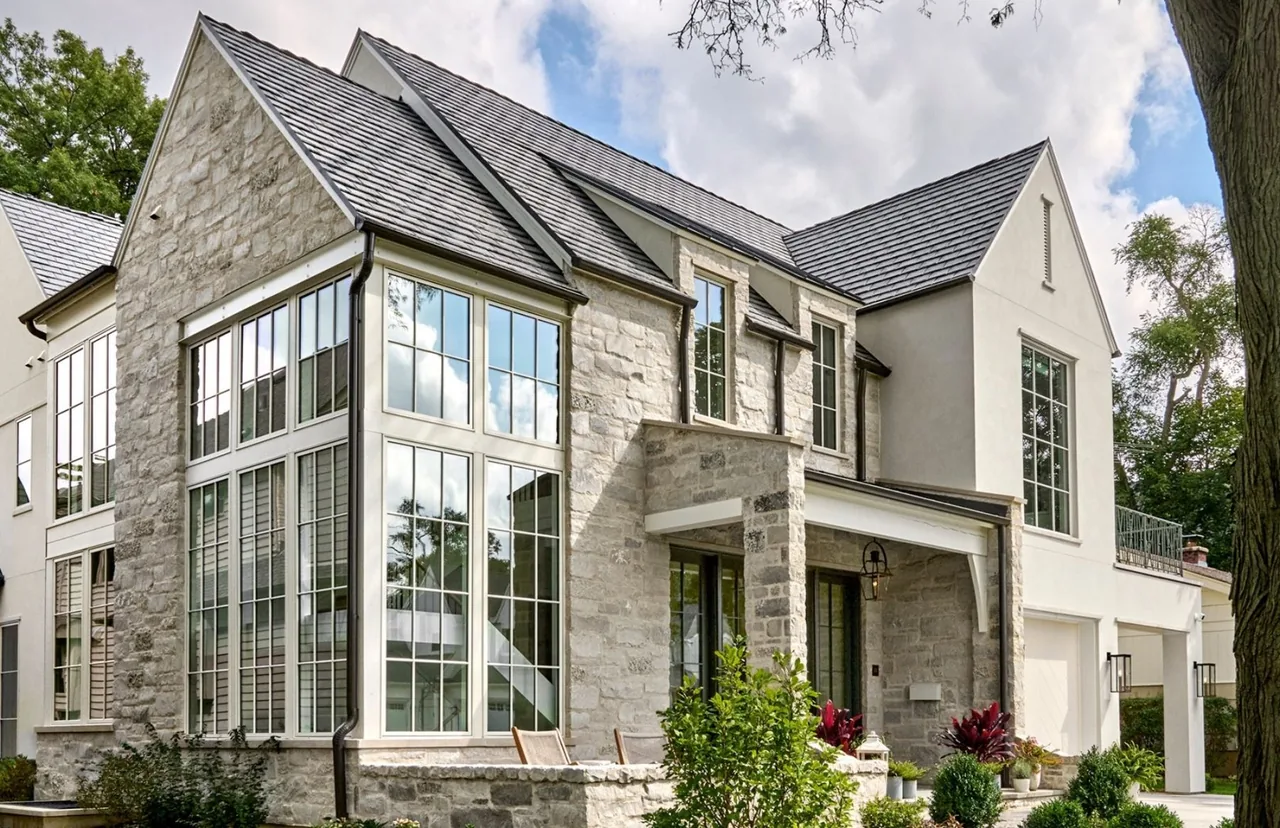 Naperville transitional residence features stone and stucco exterior walls with large divided-lite windows and gable roofs.