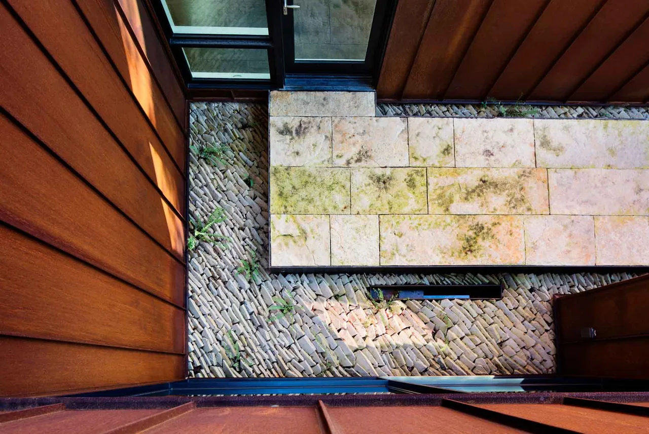 The Austin project by Chris Cobb Office of Architecture includes a courtyard with rusty metal siding and stone tile paving.