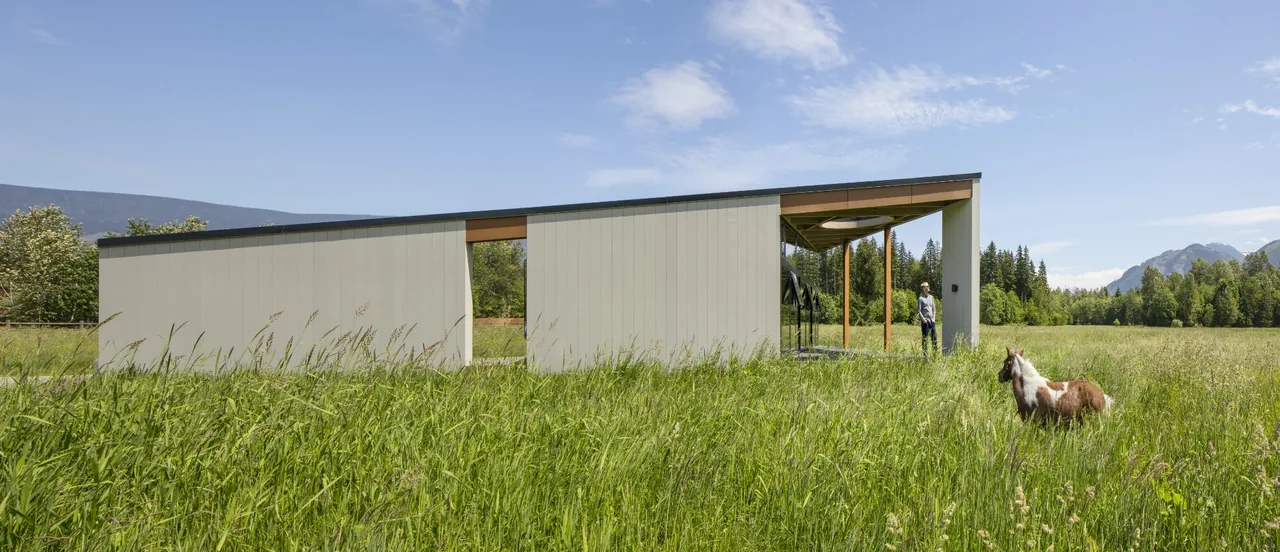 Field House by David Coleman Architecture features angled walls and large horizontal windows in a natural field setting.