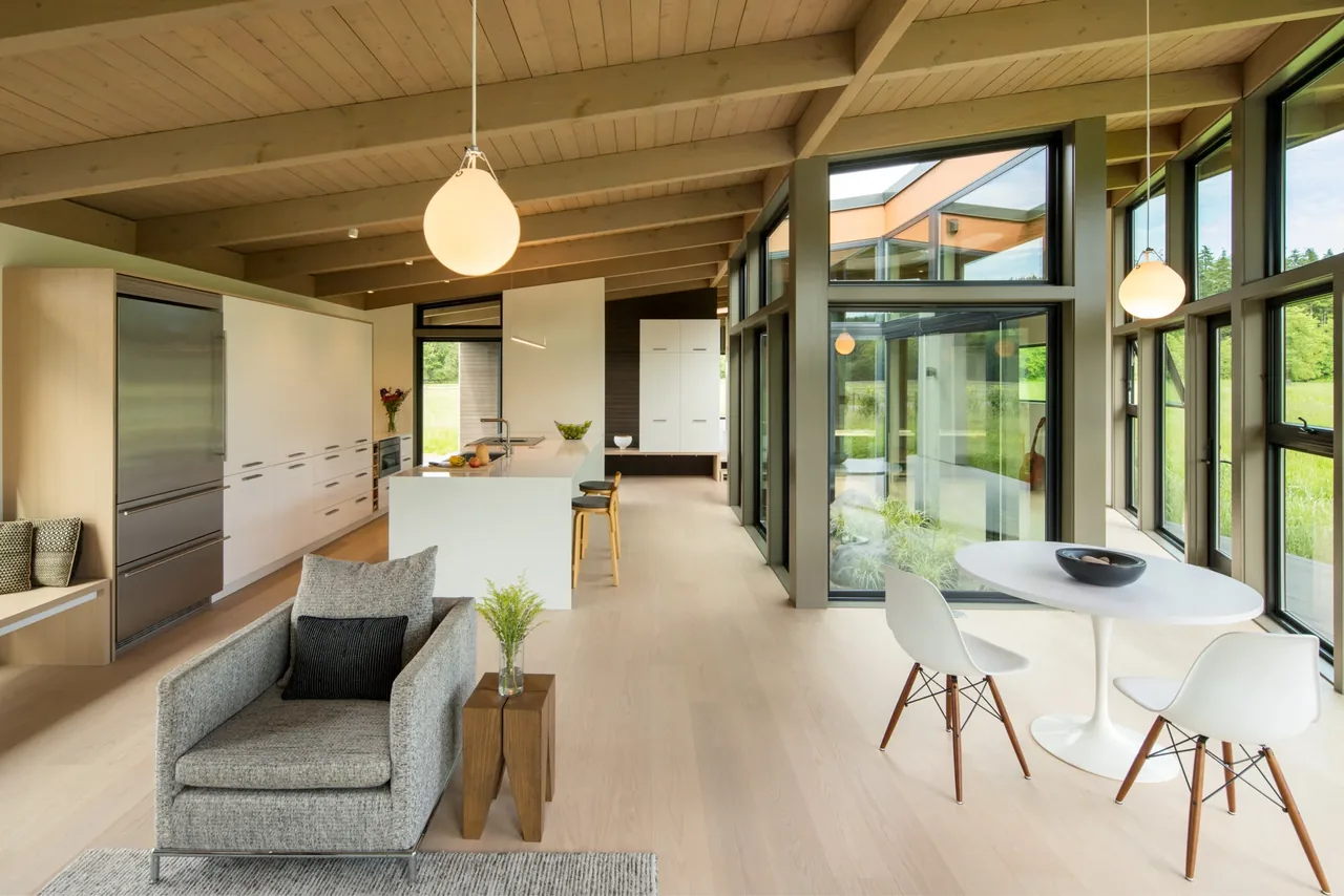 Field House features a modern kitchen and dining area with wood beams and extensive glazing designed by David Coleman Architecture.