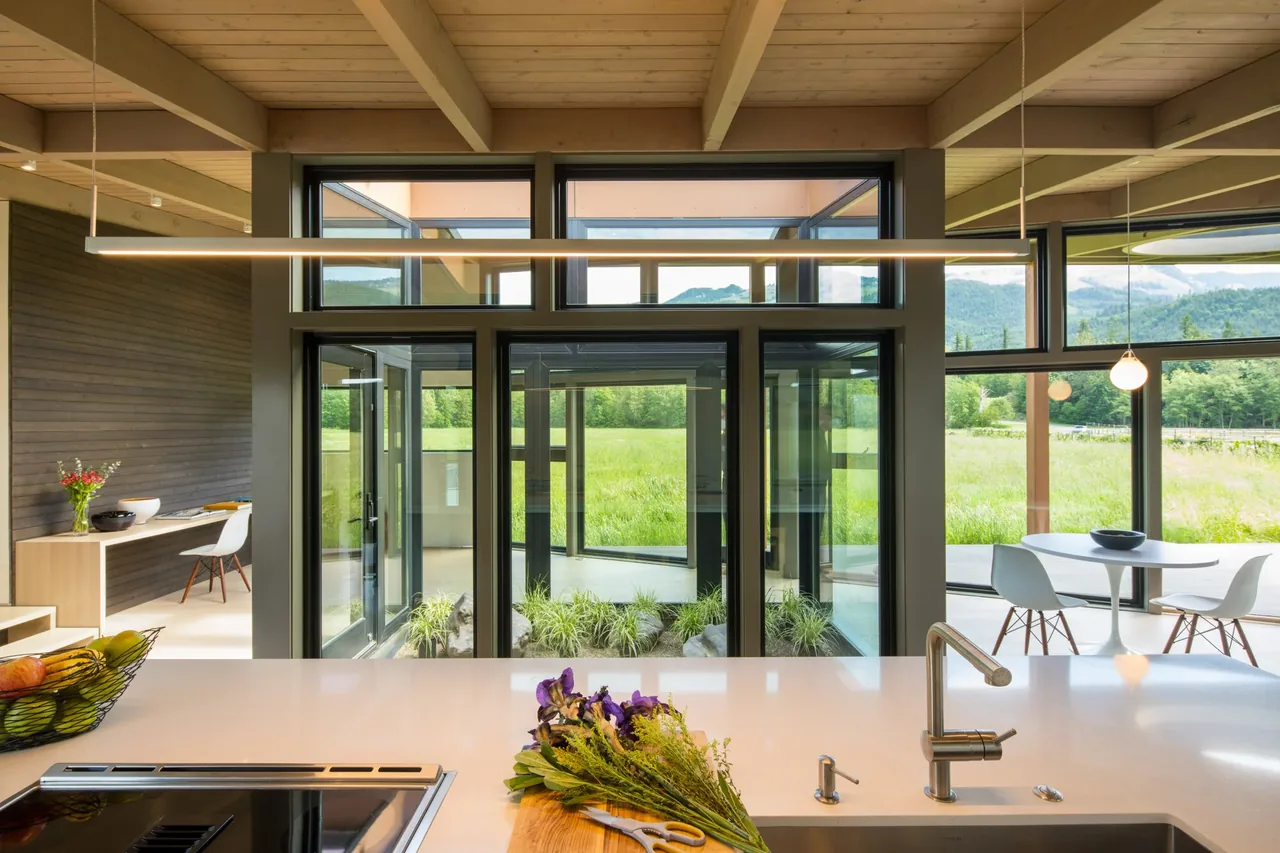 Field House by David Coleman Architecture features large metal-framed doors and windows opening to lush landscape views.