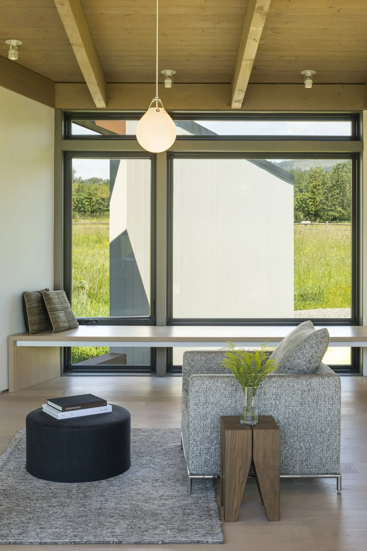Living area in Field House by David Coleman Architecture featuring wood beam ceiling and large horizontal windows with metal frames.