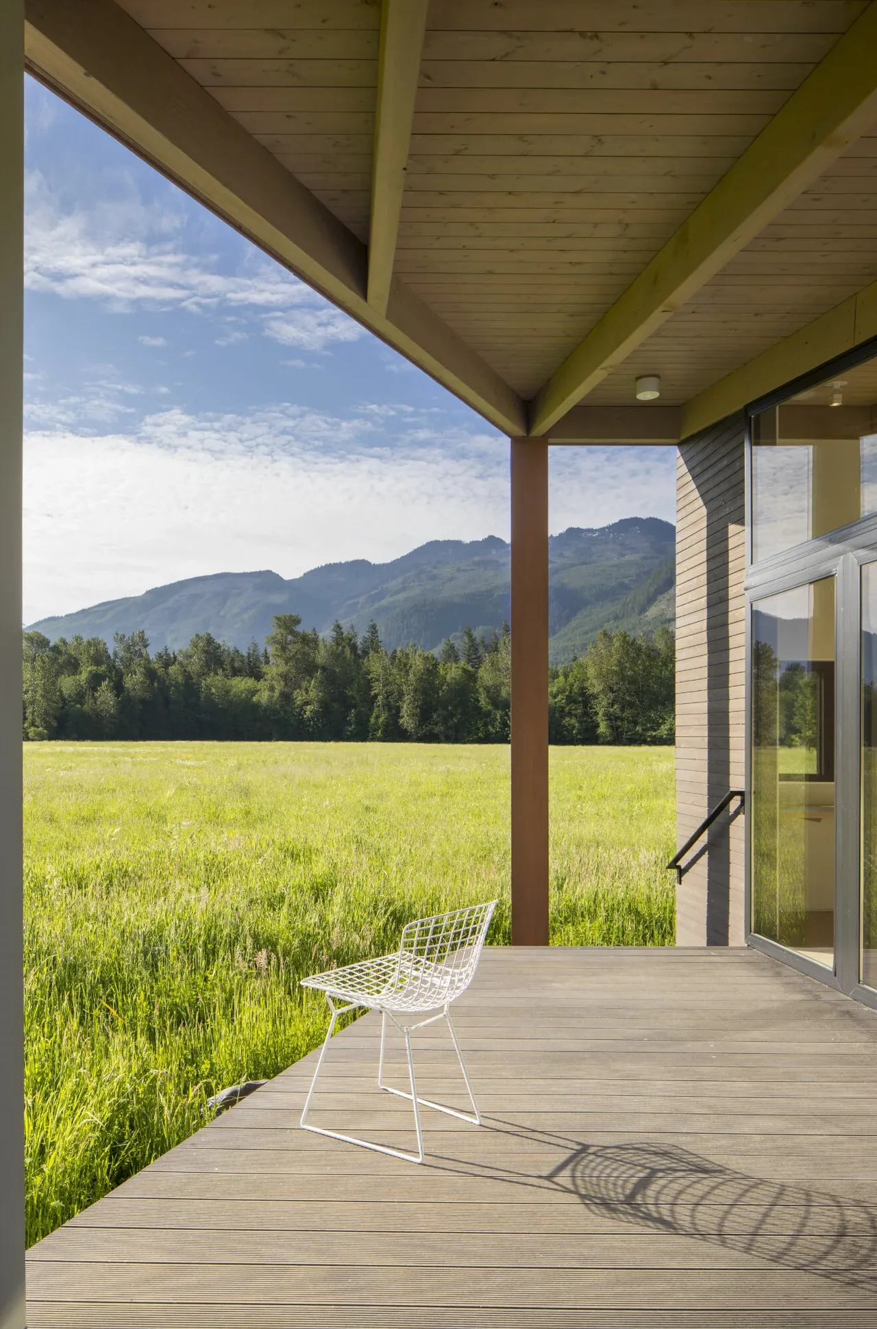 The covered patio of Field House features a wood-beam ceiling and a view of rural landscape and mountains.