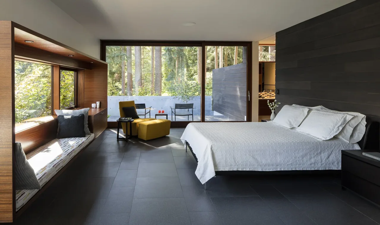 Bedroom with dark gray tile floor, wood window seating, and large framed glass door opening to an outdoor patio.